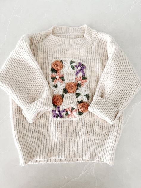 These fully customizable hand embroidered letter sweaters are sure to be the perfect gift or addition to any of the sweet littles in your life. Perfect for baby showers, name announcements, milestones, birthdays, and more. Sweaters are made of a chunky knit with a more oversized/relaxed fit. Great for spring, fall, and winter. Choose the color and size of the sweater you would like, some sweater sizes may vary based on color. Fill in the personalization box with the letter and flower colors. --- Hand Stitch Name On Sweater, Personal Baby Gifts, Embroidered Baby Sweater, Embroidery Sweaters, Hand Embroidered Sweater, Hand Embroidered Gifts, Clothes Embroidery Diy, Personalized Sweater, Custom Sweaters