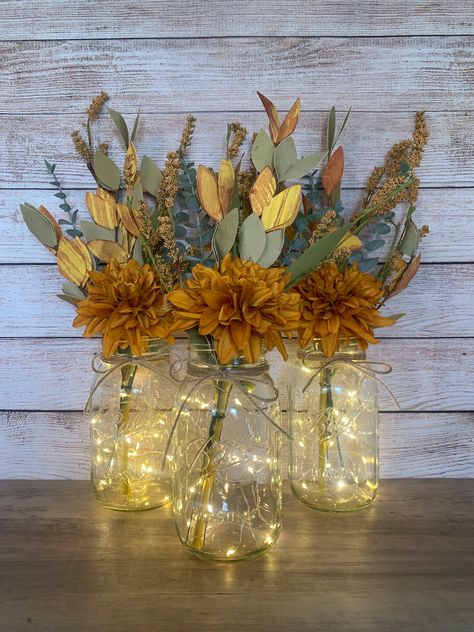 These festive fall mason jar centerpieces are a perfect addition to your autumn decor! Also ideal for a fall wedding or fall bridal shower.  Mason Jars are Ball Regular Mouth Quart Size jars.  Each floral arrangement will include - a rust colored mum pick, three eucalyptus stems and a yellow paper stem with branches of orange and yellow colored leaves.  A piece on twine will be tied to the top of each jar. And a 7ft set of warm white fairy lights will be included for each jar if purchase when ch Fall Mason Jar Arrangements, Simple Fall Centerpieces For Table, Farmhouse Autumn Decor, Fall Decor Table, Fall Mason Jar Centerpieces, Harvest Dinner, Chicago Baby, Warm White Fairy Lights, Eucalyptus Stems