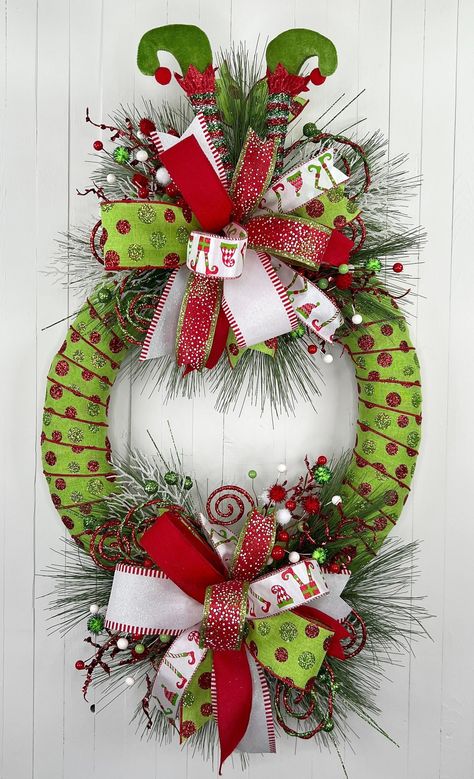 "This fun, red/white/green, whimsical Elf Christmas wreath will bring the feeling and fun of the holidays right to your front door! This is a unique, one-of-a-kind design that will be the envy of your neighborhood. Wreath is handmade and ready to ship! Holiday wreath is made on a straw wreath base that is adorned with polka dot holiday ribbon/bows, plush Elf legs, faux pine accents, red/white holiday accents. Wreath Measurements: 15\"W x 29\"H x 9\"D Wreath is ready to 📦 and 📬 to YOU today! **FREE SHIPPING IS OFFERED FOR LOWER 48 US STATES ONLY** 💕 I use high quality materials and put a special touch of TLC in every wreath I design. My wreaths are ideally suited for an indoor or covered outdoor setting. 👉 Visit Up North Wreath Designs @ www.UpNorthWreathDesigns.Etsy.com to see other wr Christmas Wreath Snowman, Pool Noodle Christmas Wreaths, Elf On The Shelf Wreath Ideas, Red Mesh Christmas Wreath, Elf Legs Wreath, Peacock Christmas Wreath, Christmas Wreath Themes, Paint Stick Wreath, Evergreen Wreaths For Christmas