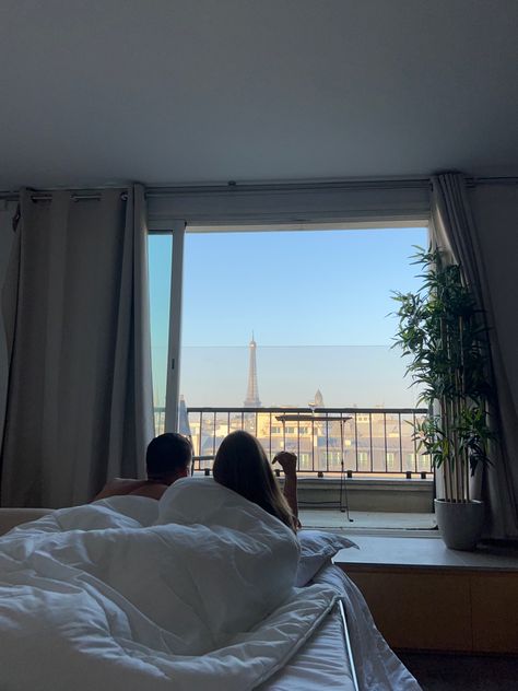 Couple laying in bed looking at the balcony where you can see the eiffel tower. Honeymoon In Paris Aesthetic, Paris Aesthetic Honeymoon, Caring Man Aesthetic, Europe Honeymoon Aesthetic, France Couple Aesthetic, Hotel Aesthetic Couple, French Couple Aesthetic, Paris Honeymoon Aesthetic, Europe Couple Aesthetic