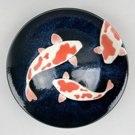 Enhance your tablescape with an authentic Japanese touch using the Koi Gunjo Ramen Shallow Flared Bowl Serving Bowl. Featuring a deep navy glaze and iconic images of three beautiful swimming koi fish, perfect for serving ramen, entrees, or as a decorative piece. Directly sourcing from Japan. SPECS: Material: Ceramics Size: 9.75"dia. x 3" height (48 oz) Weight: 1.58 pounds Dishwasher and microwave safe New Made in Japan Item Code: J6201 SPECS: Material: Ceramics Size: 9 3/4" dia. x 3" tall (48 oz Koi Fish Ceramic Art, Japan Ceramic Pottery, Designs For Ceramics, Koi Pottery Painting, Glazed Ceramic Bowls, Japanese Ramen Bowl Ceramic, Clay Dish Painting Ideas, Ceramic Bowl Inspiration, Koi Fish Ceramics