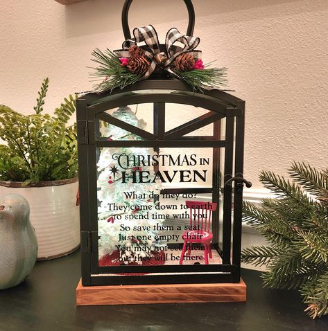 SHIPS FAST & FREE! New this year:  choose battery or new plug-in version in either clear or multicolor lights! **Be careful to select the correct options when ordering.** Beautiful way to honor a missed loved one throughout the holidays, reminding us they are always near. Elegant rectangular metal lantern has tall glass windows and narrow grilles across the front and back, a wood base, and a door that opens with a latch. Large in presence, measuring 14.25" tall (17.5" with the handle), 9.5" wide, and 6" deep.   Beautiful "Christmas in Heaven Poem" stands out in black on the front glass.  Inside is a cozy scene with miniature red chair, 8" snowy tree adorned with lights and berries, and a faux "wood" floor. Finished with b/w buffalo check bow, holiday greenery, pinecones and berries.   Also Christmas Memory Lantern, Christmas Lantern Ideas, Christmas In Heaven Poem, Christmas In Heaven Lantern, Memory Lantern, Faux Wood Flooring, Memorial Lanterns, Holiday Greenery, Christmas In Heaven