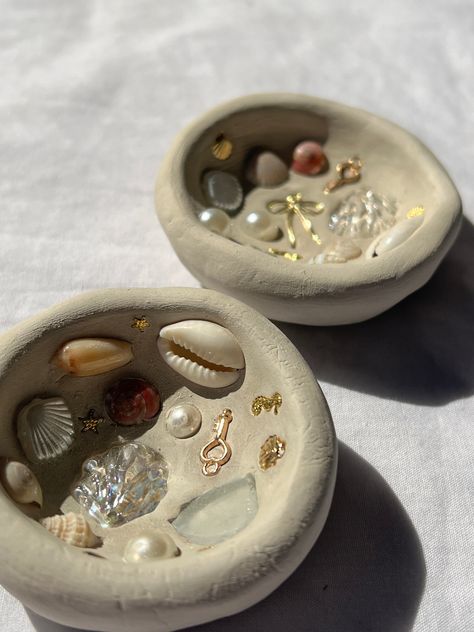 Clay shell and charm jewelry dishes Pottery With Shells, Clay Crafts Ocean, Clay Ideas Tray, Small Clay Creations, Polymer Clay Trinket Dish Diy, Air Dry Clay Trinket Dishes, Mermaid Pottery, Diy Air Dry Clay Projects, Small Clay Projects