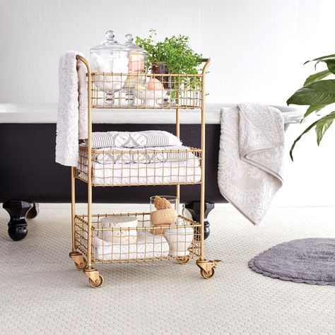 If vanity space is scarce and you have minimal floor real estate to fit your necessities, try a three-tier wire cart. The gold finish on this one adds a touch of luxe while the slightly wavy weave adds a little extra decoration. Plus, the wheels allow the cart to hold things you might for other rooms in your home. #marthastewart #organization #declutteringtips #homedecorideas #details Bathroom Storage Cart, Ikea Molger, Bathroom Cart, Rangement Makeup, Gold Bar Cart, Bar Cart Styling, Smart Tiles, Cart Decor, Rolling Storage