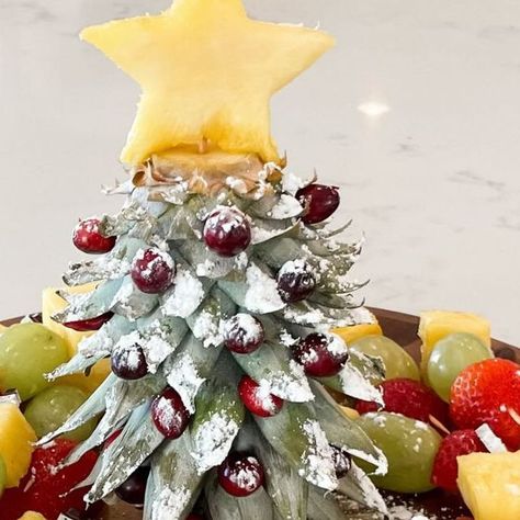 Kelsi || Content Creator on Instagram: "🎄 Christmas Tree Fruit Platter 🎄⁣ ⁣ This is THE cutest and easiest way to serve fruit at all your holiday parties!! Cut the stem off the pineapple and turn it upside down to make a Christmas tree!! I added cranberries as ornaments, a pineapple star on top and powdered sugar as snow! Inspo from the amazing ⁣@created.at.home .⁣ .⁣ .⁣ .⁣ #christmas #christmastree #christmasideas #christmastime #christmasinspiration #christmasinspo #holiday #christmasdiy #diychristmas #holidayhosting #holidayhome #christmasrecipes" Pineapple Christmas Tree Fruit Display, Pineapple Xmas Tree, Pinapple Tree Christmas, Pineapple Serving Ideas, Christmas Fruit Trays Creative, Pineapple Top Christmas Tree, Pineapple Christmas Tree Fruit Tray, Pineapple Tree Fruit Display, Fruit Christmas Tree Platter