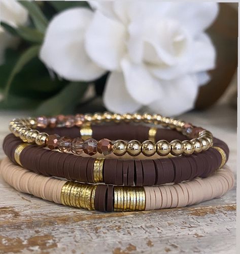 This is a chic stack of 3 Heishi bracelets... one neutral with light gold spacers and a section of brown  Heishi, and a  brown with light gold spacers and a 4mm gold ball bracelet with beautiful bronze / brown crystals. Such a gorgeous stack!  gold filled beads  Sizes are small 6.5 Medium 7  Large 7.5  - if you need smaller or larger please let me know!  Please keep out of water, no chemicals, bathing or swimming with them on. Brown Bead Bracelet Ideas, Gold Ball Bracelet, Neutral Bracelets, Brown Crystals, Heishi Bracelets, Stacked Beaded Bracelets, Brown Bracelet, Clay Bracelet, Bracelets Diy