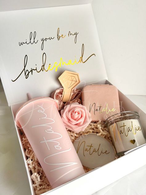 These beautiful pink and gold themed deep large filled boxes make the perfect gift for your bride tribe, packed with an excellent variety of personalised goods these are sure to make the best surprise! Value works out much better than purchasing each item individually! Details: EVERY ORDER COMES WITH: -White magnetic box: 11"x8"x4" Personalised with gold name and inside message. Comes with ivory crinkled paper inside. Tied with pink frayed ribbon. -Pink foam rose ITEMS INCLUDED IN BOX WILL VARY Cute Gifts For Bridesmaids, Bride Made Gifts Ideas, Cricut Wedding Bridal Party, Bridesmaid Proposal Box Ideas Purple, Gifts For Bridesmaids From Bride, Bride To Be Hamper Ideas, Bridesmaid Hamper Ideas, Bridesmaid Box Ideas, Crinkled Paper