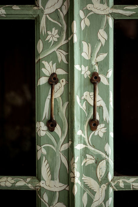 A masterpiece of craftsmanship and design collaboration, the Birdie pieces feature a delicate scene depicting birds and vines, designed in-house and beautifully executed in India. Featuring a hand painted pattern atop HMcG colour Hampstead Green, glazed double doors with antique gold hardware, charming saber legs, three shelves and original teak interior. #handpainted #antiquefurniture #rusticfurniture #furnituredetails #brasshardware #greenfurniture Painted Cabinet Interior, Gold Doors Painted, Diy House Paint Interior, Diy Paint Wardrobe, Hand Painted Doors Ideas, Pattern On Pattern Interior Design, Mushroom Painted Furniture, Antique Interior Doors, Hand Painted Dresser Ideas