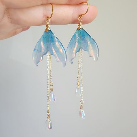 Discover the beauty of iridescent mermaid tail earrings in this stunning collection. These unique and eye-catching accessories are sure to make a splash wherever you go. Perfect for adding a touch of whimsy and magic to any outfit. Whether you're attending a wedding, a formal event, or simply want to add a touch of fierceness to your everyday look, these earrings are a versatile and stylish choice. 🍊Material: The earrings are made with shimmering resin mermaid tails, Czech glass water drops and the 14K gold plated (nickel-free) hooks. Handmade in Maryland, USA! 🌺Size: approx.(W x L) 2.54cm x 9.5cm 🎀Handmade jewelry: Each item is made to order, which gives our pieces a unique meaning that is specific and special to you.Therefore, there are no two items exactly alike. Contains small parts Mermaid Tail Craft, Mermaid Accesories, Hoverboard Girl, Graduation Accessories, Water Accessories, Mermaid Tail Earrings, Magic Earrings, Coworker Appreciation, Magical Earrings