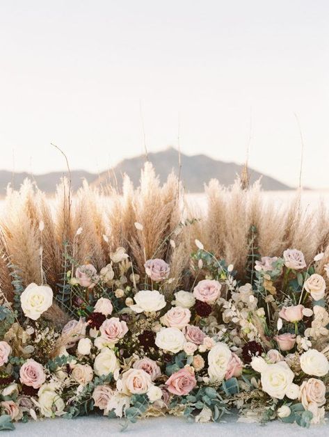 pampas grass and rose-filled floral installation Pampas Grass Wedding Bouquet Spring, Pampas And Pink Flowers, Dusty Rose Pampas Wedding, Pampas Flower Wall, Spring Pampas Grass Wedding, Pampas And Roses Centerpiece, Matrimonio Pampas, Pampas And Roses, Pampas Grass And Roses