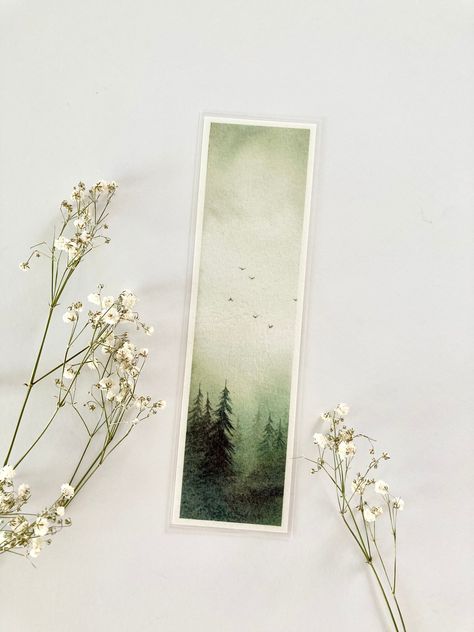 - DESCRIPTION -  One bookmark featuring my original watercolour forest painting. The perfect companion for wherever your next reading adventure takes you!  Printed on fine art paper using archival inks and laminated for protection. Perfect as a gift for any occasion: Christmas, birthday, anniversary etc. or to treat yourself.    Bookmarks will be packaged securely inside a clear sleeve in a rigid cardboard mailer for protection.  **Please note that colours may vary slightly from what you see on your screen.  **Features my original watercolour painting.  Dimensions - 5.5 x 19cm approximately  Thank you for visiting my shop! All artworks are painted with love by me in my studio. Please feel free to contact me if you have any questions.  Follow me on instagram for updates and more: @jodieoste Forest Bookmark, Watercolour Notebook, Watercolour Forest, Watercolour Bookmarks, Nature Bookmark, Bookmark Ideas, Reading Adventure, Winter Watercolor, Watercolor Bookmarks