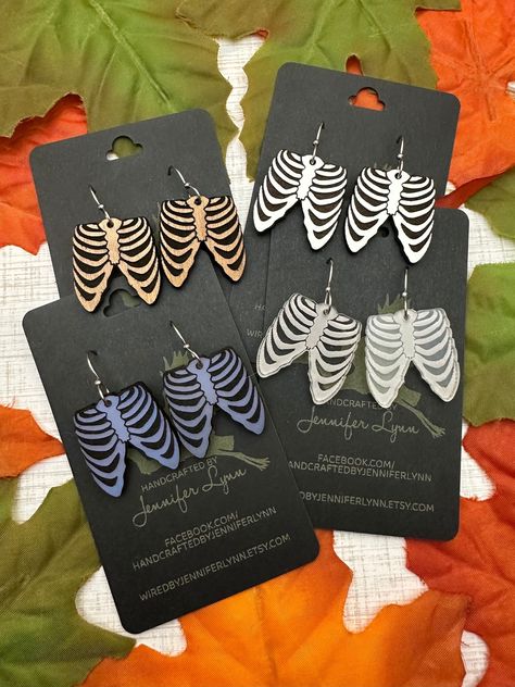 These boney rib cage earrings are laser engraved from either acrylic or maple ply. The result is a pair of spooky-fun earrings that are perfect for Halloween and all spooky season long!  OPTIONS INCLUDE:  - CHERRY WOOD - Laser cut from a piece of cherry ply, the engraved area is painted with a matte black that adds a distressed look to the wood.  - WHITE - Cut from a piece of white eucalyptus board. The white is slightly textured and the engraved portion is a dark brown. The backside of the earr Halloween Laser Ideas, Laser Halloween Ideas, Unique Laser Cut Ideas, Xtool S1 Project Ideas, Halloween Laser Projects, Laser Engraving Ideas, Laser Cut Projects, Laser Cut Halloween, Laser Earrings