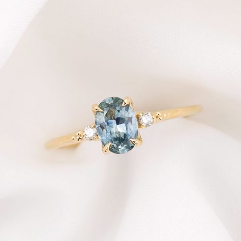 * One of a kind ring * In stock ready to ship in size 7.25 * 0.93ct Oval Cut Montana Sapphire Light Blue 7.02x5.05x3.07mm, vvs clarity, Heated * Bandwidth: approx. 1.4mm * Natural accent diamonds 0.04ctw * Elevated four prongs flower setting * Ethically sourced solid 14k yellow gold and gemstones * Packaged in a recyclable kraft ring box Light Blue Diamond Engagement Ring, Oval Cut Sapphire Ring, Pale Blue Engagement Ring, Light Blue Engagement Rings, Light Blue Sapphire Ring, Saphire Engament Ring Gold Band, Light Sapphire Engagement Ring, Light Blue Engagement Ring, Coloured Engagement Rings