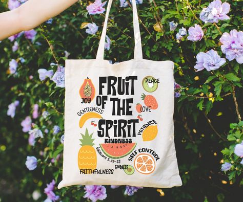 Carry your faith with our stylish Fruit of the Spirit Tote Bag. Made of durable canvas, this spacious bag features a meaningful Bible verse. Perfect for Christian girls, churchgoers, and as a religious gift. Embrace your Christian values wherever you go. Order now! This 100% cotton bag comes in one size - 15" x 16"- perfect for everyday wear. While the canvas material will show off your designs in great colors, it's durable and will last for years. The bag features 20" handles (made from the sam Sublimation Canvas Bag Ideas, Tote Bag Painting Ideas Bible Verse, Christian Tote Bags Paint, Bible Tote Bag Diy, Bible Bag Ideas, Jesus Tote Bag Painting Ideas, Diy Bible Bag, Christian Tote Bag Design Diy Paint, Bible Bags Totes Diy Paint