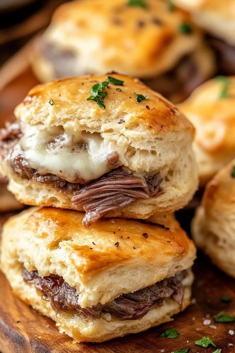 French Dip Biscuits Recipe – These flaky refrigerated biscuits are filled with tender roast beef, melted provolone, and a kick of horseradish, then baked to perfection. When they come out of the oven, brush them with melted butter for an extra layer of flavor. Serve with hot au jus on the side for dipping—absolutely delicious! French Dip Biscuits Plain Chicken, French Dip Biscuit Melts, Roast Beef Crescent Rolls Au Jus, Roast Beef Biscuits, Biscuit French Dip, Baked Roast Beef Sandwiches, Beef Brunch Ideas, Chuck Roast Appetizer, Recipes With Flaky Layers Biscuits