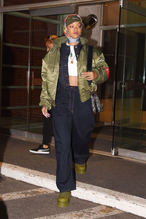 In a Supreme baseball hat, silk scarf, white ribbed crop top, denim jacket and matching oversized jeans, olive puffer jacket and Fenty x Puma boots while out in New York. 90s Chola, 90s Chola Fashion, Western Winter Fashion, Rihanna Street Style, Western Winter, Looks Rihanna, Looks Hip Hop, Rihanna Outfits, Rihanna Looks