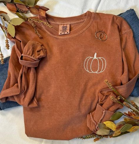 It's that time of year, you know what time...Pumpkin Time!  The days become shorter but they sure seem to slow down.  Our simple pumpkin outline tee is the perfect way to show you love the season in perfect minimalist style.   The softest and most cozy Comfort Colors tee with a cute fall style!  Pair with your favorite jeans, or size up one and grab your comfy leggings!  You are choosing Long Sleeve or Short Sleeve Shown here in the long sleeve option with cream thread.  If you prefer a differen Fall Shirts Simple, Fall Long Sleeve Shirts Vinyl, Pumpkin Patch T Shirts, Fall And Halloween Shirt Ideas, Fall Embroidery Shirts, Thanksgiving Graphic Tees, Cute Tshirt Designs For Women, Fall Cricut Shirts, Embroidered Shirt Ideas