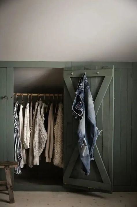 a sloped ceiling nook with green shiplap doors that hide railing for clothes is a smart solution for a farmhouse space Closet Sloped Ceiling, Slanted Closet Ideas, Closet With Slanted Ceiling, Shiplap Doors, Green Shiplap, Slanted Ceiling Closet, Sloped Ceiling Closet, Attic Closet Ideas, Corner Closet