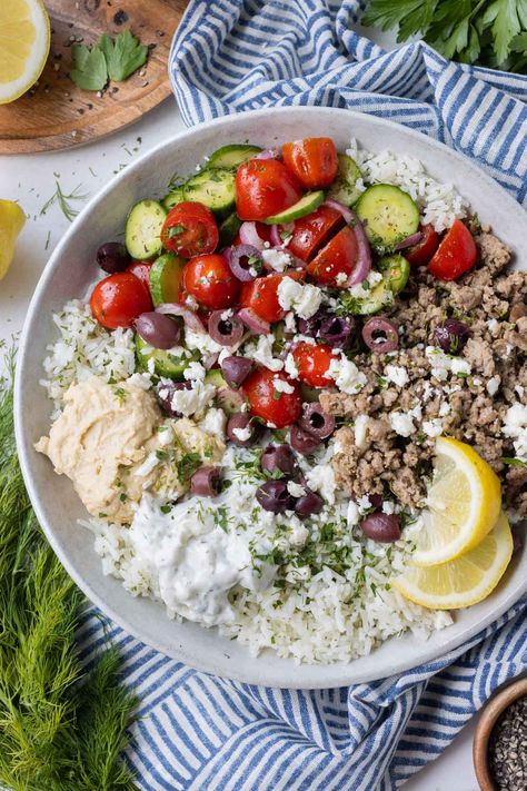 These Greek Ground Turkey Rice Bowls are bursting with fresh Mediterranean flavor from a homemade Greek seasoning mix—the secret to why the ground turkey tastes so incredible! Paired with bright lemon and herb rice, a cucumber tomato salad, and a duo of tzatziki sauce and hummus, they are one of our go-to meal prep options on busy weeknights—even picky eaters give this one two thumbs up! Ground Turkey Tzatziki Bowls, Greek Ground Chicken Bowls, Ground Turkey Recipes For Dinner Mediterranean, Greek Bowls Ground Turkey, Greek Turkey Rice Bowl, Mediterranean Diet Recipes With Ground Turkey, Ground Turkey Mediterranean Bowl, Turkey Greek Bowl, Ground Turkey Gyro Bowl