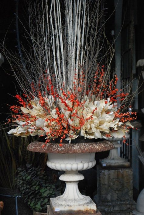 Dramatic flower arrangement for winter wedding: orange winterberry, white lilies and dry branches/ grass. I'd put uprights around it for after dark, and hide something sparkly in the arrangement - would look even more dramatic after nightfall!