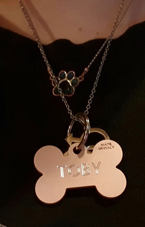 A necklace with a mood ring style paw pendant and another necklace with a custom engraved bone shaped dog tag that reads "Toby" as well as a homosexual man pendant on it Dog Bone Necklace, Dog Tag Necklace Aesthetic, Therian Jewelry, Dog Boy Aesthetic, Therian Necklace, Therian Accessories, Puppyboy Aesthetic, Therian Paws, Dog Therian