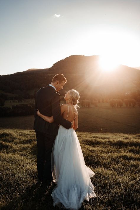 Couple looking at each other with the sun setting behind the mountains in front of them. If you want to plan your wedding for sunset, check out this guide! Couple Looking At Each Other, Outdoor Wedding Pictures, Mountain Wedding Photos, Sunset Wedding Photos, Barn Wedding Photos, Looking At Each Other, Wedding Portrait Poses, Wedding Couple Photos, Wedding Picture Poses