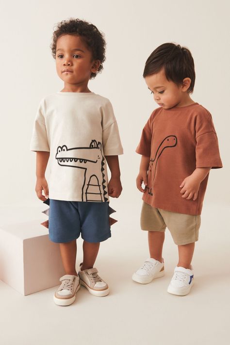 This stylish 2-piece t-shirt and shorts set features a rust brown dinosaur t-shirt and blue jersey shorts with 3D dinosaur scales along the side hem, alongside an ecru cream crocodile t-shirt with coordinating neutral shorts, crafted from pure cotton. The tops boast a drop shoulder and crewneck collar, whilst the shorts have an adjustable elasticated waistband. T-shirt CEMENT, T-shirt RUST, Shorts BLUE and Shorts CEMENT 100% Cotton. Kids T Shirt Animals, Brown Dinosaur, Cool Boys Clothes, Kidswear Trends, Safari Outfits, 3d Dinosaur, Kids Tshirt, Blue Jersey, Boy Clothing