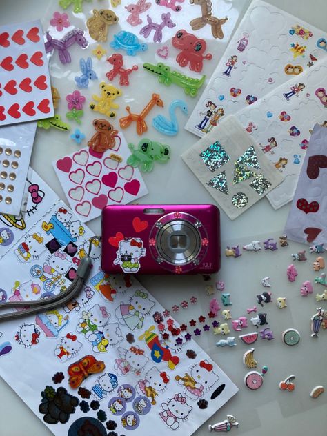 A old, pink digital camera decorated with colorful heart, hello kitty, gemstone, fruit stickers Stickers On Digital Camera, Digital Camera Aesthetic Stickers, Decorated Camera Aesthetic, Digital Camera With Stickers, Decorate Digital Camera, Digital Camera Stickers, Decorated Digital Camera, Digital Camera Decorated, Decorated Camera