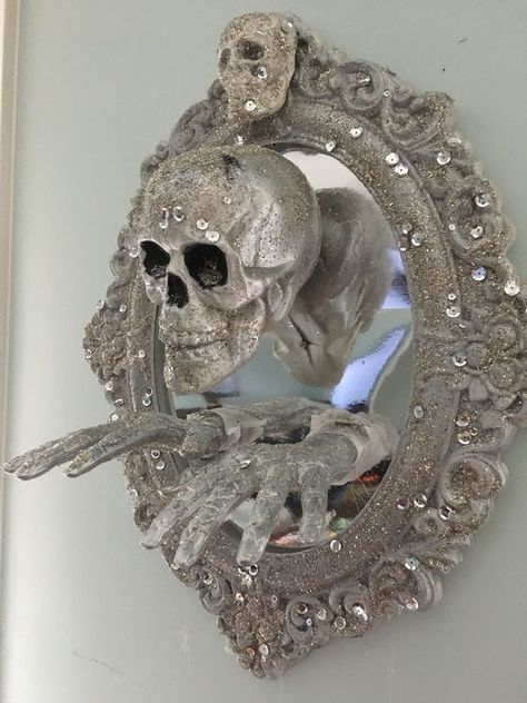 a mirror in a chic glitter and rhinestone frame, with a glitter skull and hands is a cool decor idea for Halloween Halloween Scene Ideas, Halloween Mirror Decor, Couture Halloween, Skull Decorations, Halloween Mirror, Fun Diy Halloween Decorations, Glitter Skull, Scary Halloween Decorations Diy, Mirror Decor Ideas