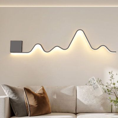 The wall sconce lighting fixture designed in a unique wavy and linear structure shape, add more fashion elements to your house, blends with most types of home decoration style. This modern wall sconces have a memory function. When you turn it on, it will maintain the lighting mode you turned off last time. And its light color and brightness can be adjusted. | Wrought Studio™ Heidamos 1 - Light 43.3" Aluminum LED Flush Mounted Sconce Metal in Black / White | 7.08 H x 43.3 W in | Wayfair Entryway Wall Lights, Modern Ambient Lighting, Wall Lights Behind Sofa, Wall Art Lighting Ideas, Dining Room Wall Lighting, Creative Bedroom Lighting, Lights Behind Couch, Neon Sign Living Room Decor, Pictures With Lights On Wall