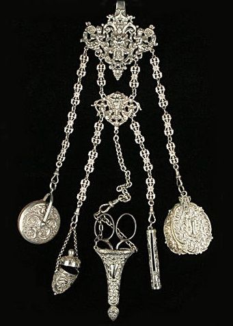 A Victorian chatelaine by George Unite, Birmingham 1899. The belt hook pierced and chased with mask and cherub scrolls, with five chains supporting a floral chased pin wheel, by George Unite, Birmingham 1898; an egg-shaped floral chased thimble case, by George Unite, Birmingham 1898; an electroplate scissor sheath with steel scissors; an electroplate pencil, and an electroplate carnet. 18th Century Jewelry, Old Pocket Watches, Victorian Accessories, Belt Hook, Vintage Pocket Watch, Medieval Jewelry, Tool Belt, Vintage Purses, Chatelaine