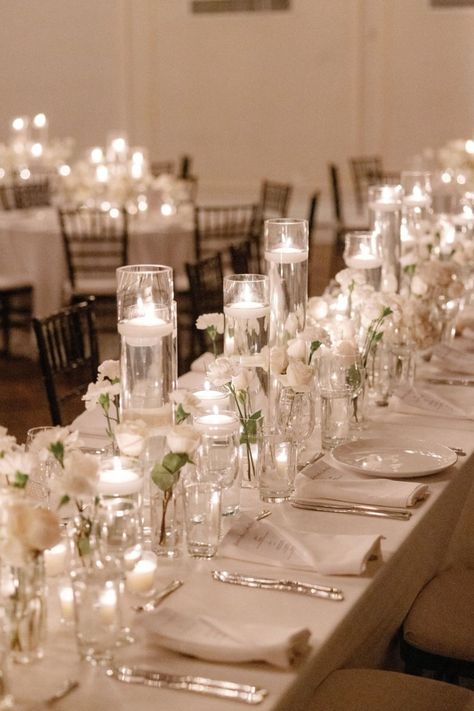 A stunning reception setup featuring delicate white florals and glowing candlelight, creating an atmosphere of romance and sophistication. Perfect for a timeless wedding celebration. #CandlelitWedding #ElegantReception #WhiteFlorals #RomanticAmbiance #WeddingInspiration White Candle Lit Wedding, White And Candle Wedding, Wedding Round Table Candles, Small Indoor Reception, Candle Decor For Weddings, Reception Table Decorations Simple, Reception Set Up, Classy Indoor Wedding, Wedding Table With Candles