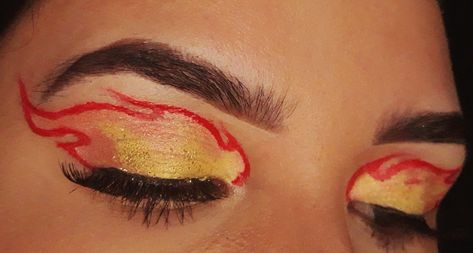 Olhos com uma chama de fogo desenhado em vermelho, com sombras laranja e amarelo dentro do formato, com glitter amarelo e cílios postiços Fireball Makeup Looks, Flame Outfit Aesthetic, Fire Flame Costume, Firefighter And Flame Costume, Flame Princess Makeup, Flame Halloween Costume, Flames Makeup Look, Simple Dragon Makeup, Rengoku Makeup Inspired