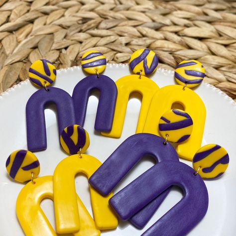 "Purple & Gold Arch Clay Earrings | Polymer clay earrings, Game day jewelry, School spirit, Gifts for her | \"The Amy\" Purple & gold tiger stripe earrings, perfect for the LSU fan! The arch shape is minimalistic in design and great for all women. Earrings make the perfect gift for any woman in your life; moms, sisters, daughters, girlfriends, and teachers! Everyone loves getting a handmade item.  The earrings are available in two sizes, small and large. The small earrings measure just under 2 i Clay Lsu Earrings, School Spirit Clay Earrings, Lsu Earrings, Jewelry School, Earrings 2023, Gold Tiger, Diy Earrings Polymer Clay, Spirit Gifts, Arch Shape