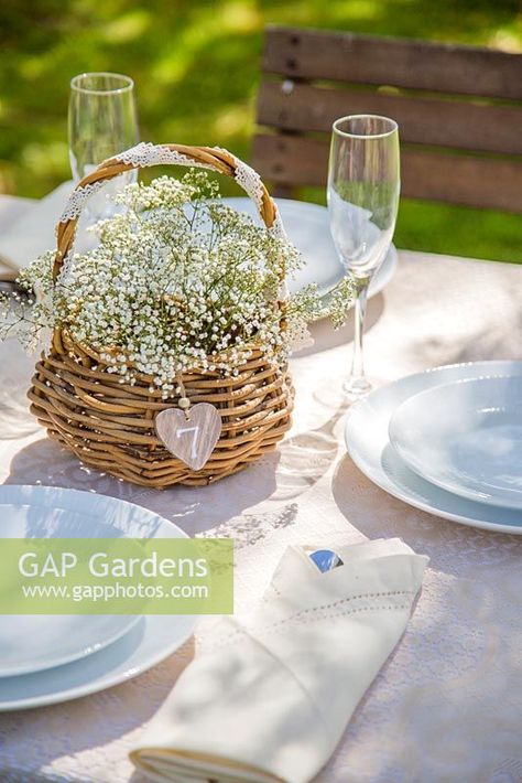 Wicker basket of Gypsophila used as a table setting. Basket Of Flowers Centerpiece, Simple Garden Birthday Decor, Basket Wedding Centerpieces, Wicker Basket Centerpiece Ideas, Picnic Basket Flower Arrangement, Basket Centerpieces Table Wedding, Flower Basket Centerpieces, Wicker Wedding Decor, Basket Centerpieces Table