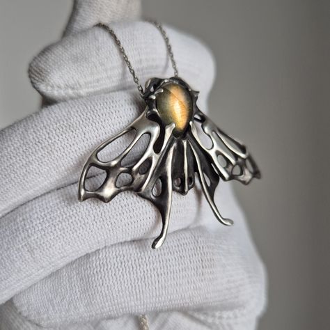 The Aurora moth pendant, ready to ship. Sterling silver, oxidized for depth and contrast; handmade. Features a labradorite cabochon with a dark gray body and bright golden flash. The Moth  image perfectly reflects one of the core concepts which drives my work--rebirth, transformation, continuity, and the cyclical nature of life. It's a symbol of ongoing development. I sought to capture my admiration for the intricate and ornamental beauty of nature. . Please note! Chain is not included. ✈️ Shipping from Thailand. Please kindly allow 2-4 weeks to arrive. ... About 5 cm/1,97 inch long Only 1 available Nature Inspired Jewelry Necklaces, Moth Clothing, Silver Clay Jewelry, Witch Amulet, Halloween Moth, Moth Jewelry, Moth Pendant, Cabochon Necklace, Silver Jewelry Necklace