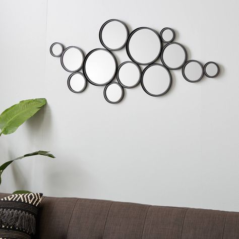 "Buy this 52\" Black Contemporary Metal Wall Mirror Cluster at Michaels. com. If you're looking for unique yet versatile accent decor for your walls, this cluster of lively contemporary round mirrors will bring you the style boost you need. If you're looking for unique yet versatile accent decor for your walls, this cluster of lively contemporary round mirrors will bring you the style boost you need. Thirteen small, medium and large round metal mirrors are welded together in a whimsical staggere Bubble Mirrors Wall Decor, Round Mirrors On Wall, Mirrors On Wall, Wall Spheres, Colored Entryway, Floating Bubbles, Colorful Contemporary Art, Den Decor, Metal Wall Mirror