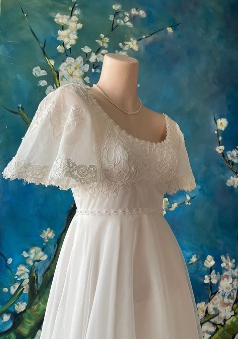 Romantic Regency 1950s Chantilly lace wedding gown with Jane Austen vibes and Edwardian style back bustle with a delicate bodice, tiny white satin ribbon bows at sleeve and back . A sweet scalloped lace at neck, frames the decolletage so softly. A little piped edge runs around the high waist for added interest. Tiny mini pearl beads are attached at bodice front and sleeves. There is lace that runs along the edge of the full lace skirt and train that creates a bustle effect at the back, almost an Edwardian inspired style. The under dress has turned an off white that accents the white lace beautifully. Metal zipper closure at back with an under slip netting at bustle for just the right fullness. This fabulous dress has been professionally cleaned and is in near MINT condition for its age! Th Wedding Dress Sleeve Types, Vintage Wedding Dress Long Train, Sleeves Ideas For Dress, 1950s Lace Dress, 19th Century Inspired Wedding Dress, Flutter Sleeves Dress, Wedding Dresses Satin Modest, Wrist Loop Wedding Dress, Regency White Dress