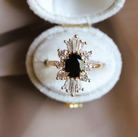 The Decora Oval Halo Ring is a true statement of elegance and sophistication, expertly crafted in a vintage-inspired design. She is boasting a stunning 1 ct. oval center stone of your choice (Black Diamond or Black Onyx), complemented by a delicate halo of tapered baguette and round diamonds, The raised cathedral design allows for seamless stacking with a straight wedding band, making it an ideal choice for an engagement ring. This engagement ring is sure to capture everyone's attention. Upgrade your proposal with a touch of timeless beauty. -------------------------------------------- ✦ MAIN STONE: Choice Of  ✧ Conflict-Free Natural Black Diamond ✧ Natural Black Onyx ✧ Shape & Cut: Oval/Faced ✧ Gemstone Size: 8 x 6 mm / 1 ct. approx. ✦ ACCENT STONE:  ✧ Lab-Grown Diamond ✧ Clarity/Color: V Diamond And Onyx Engagement Ring, Black Stone Engagement Ring, Victorian Style Engagement Ring, Halo Engagement Ring Oval, Black Diamond Halo Ring, Cathedral Design, Diamond Ring Oval, Oval Halo Ring, Birthday Jokes