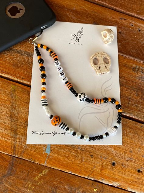 "I drew my orange wooden beads with a pumpkin theme and applied a special varnish on them so that the drawing did not flow. You will be very special with my completely handmade Pumpkins Phone Case Accessory. It will not be sold anywhere else so it will be a unique Hallowen gift. While making this Halloween Pearl Phone Charm I used orange, black and white seed beads, Black and White Pearls and Polymer Clay Beads and Candy White Beads for you. I wrote to your name in black letters on a white backg Pearl Phone Charm, Beads Black And White, Halloween Beaded Jewelry, Halloween Bracelet, Halloween Beads, Bead Charms Diy, Halloween Charms, Clay Bracelet, Diy Bracelets Patterns