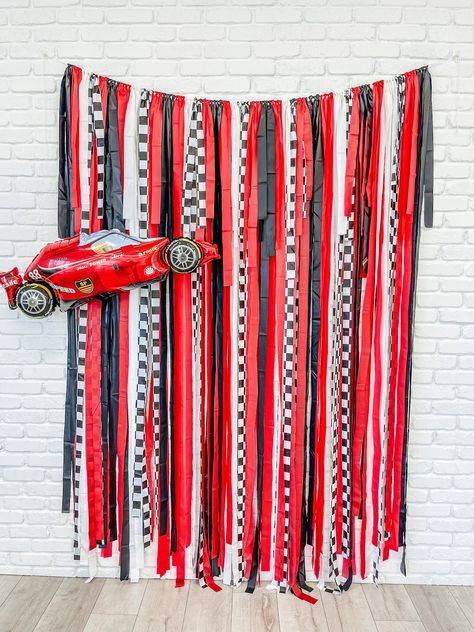 Add a touch of speed and style to your next event with our Race Car Fringe Backdrop. This eye-catching backdrop features a bold race car design in vibrant red, white, black, and checkerboard patterns. Perfect for car enthusiasts or anyone looking to inject some adrenaline into their celebration. Made from durable materials, this backdrop is available in various sizes to suit your venue's dimensions. The playful fringe detail adds an extra element of fun and movement to your event décor. Whether you're hosting a birthday party or a racing-themed gathering, our Race Car Fringe Backdrop is sure to rev up the excitement. Colors: Red, Black, White and Checker fridge.  Three sizes to choose from:  backdrop is approximately 7' in height and 4', 5', 6', 7' or 8' wide with extra rope on each side. Dirt Track Birthday Party, Race Car Party Backdrop, Racing Decorations Diy Party Ideas, Race Car First Birthday Photoshoot, Race Car Themed 3rd Birthday Party, Race Car Birthday Decor, Garage Theme Birthday Party, Racing 3rd Birthday, Racing Bachelorette Theme