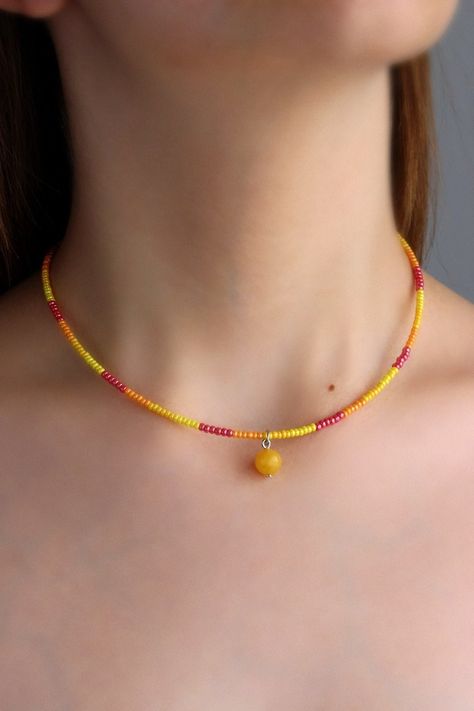 Pretty summer choker necklace with natural polished agate stone 8 mm bead, yellow, red plastic seed beads, two layers of strong nylon thread, silver tone claps and silver tone lobster claw with stainless steel chain. Perfect for everyday wear or a lovely gift! The length of necklace is about 39.5 cm or about 15.5 inches and about 4 cm of adjustable length chain. Other necklaces you can find in my store in the necklace section. https://www.etsy.com/shop/NaTavelli?section_id=14843046&ref=shopsecti Beaded Summer Necklace, Beaded Choker Ideas, Yellow Beads Necklace, Orange Necklaces, Golden Choker, Orange Beaded Necklace, Seed Beads Necklace, Summer Choker, Plastic Necklace