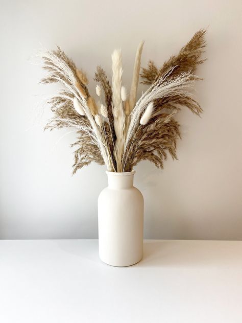 Beautiful natural dried flower arrangement including fluffy pampas and an assortment white/neutral dried flowers. The dried bouquet comes with an option to add a hand painted beige vase. The vase and pampas bouquet together are the perfect addition for any neutral/boho home decor or are ideal as a home gift.  **PLEASE READ** Vase dimensions: 20cm Tall, 10cm Wide.  Bouquet dimensions: approx 45cm tall.  Bouquet contains:  - 3 Stems fluffy natural pampas - 2 Stems white pampas - 2 Stems white misc Pampas Flower Arrangement, Tall Bouquet, Neutral Boho Home, Wide Bouquet, Pampas Flower, Beige Vase, Pampas Bouquet, Vase Beige, Lounge Inspiration