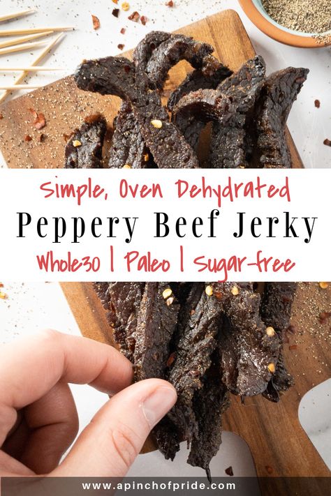 Hand grabbing a slice of peppery beef jerky. Jerky is on a wooden board sprinkled with red pepper flakes and ground pepper. There are a few toothpicks on the top left. Tag says "Simple, Oven Dehydrated Peppery Beef Jerky. Whole30, paleo and sugar-free." Simple Jerky Marinade, Beef Jerky Recipe Dehydrator, Beef Jerky Marinade, Jerky Recipes Dehydrator, Jerky Marinade, Smoked Beef Jerky, Best Beef Jerky, Jerky Recipe, Dried Beef