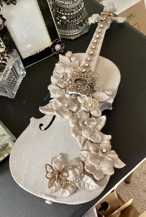 This is a vintage violin that I completely upcycled into a unique and beautiful decorative accent. The violin is painted a pale grey/beige and topped with antiquing medium. I created a cascade of resin flowers and leaves painted in the grey/beige and then dry brushed with metallic gold to highlight the details. antique gold tone and rhinestone jewels are added to make this a unique and beautiful decorative accessory for your home or as a gift for the violinist or musician in your life. For more beautiful decor, visit my shop at: https://www.etsy.com/shop/ArcMosaicsandJewels   I package very carefully however in the rare event that something arrives damaged, please take detailed photos of the item in the box, all the packaging materials ( paper and bubble), the condition of the carton and t Violin Decoration Ideas, Shabby Chic Violin, Steampunk Mixed Media Art, Vintage Violin, Floral Cascade, Turquoise Furniture, Violin Design, Violin Art, Steampunk Mixed Media