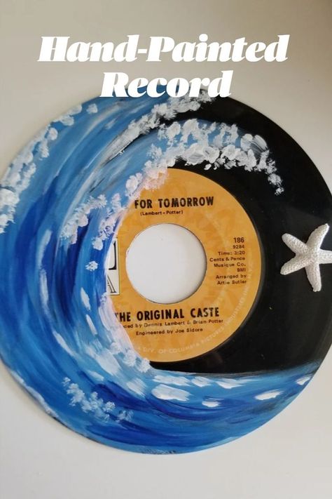 Photo shows a black vinyl 45 rpm record hand-painted with a blue and white cresting ocean wave.  There is a small white resin starfish adhered to the record for a fun touch! Records Painted, Painted Records Vinyl, Record Painting Ideas, Record Ideas, Painted Records, Painted Earth, Ocean Wave Painting, Vinyl Art Paint, Ocean Wave Wall Art