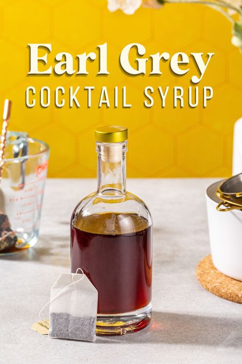 Side view of a bottle of syrup with a teabag next to it. In the background are a saucepan and tools to make the recipe. A bold text overlay says "Earl Grey Cocktail Syrup". Earl Grey Syrup Recipe, Cocktail Syrup Recipes, Earl Grey Simple Syrup Recipe, Whiskey Simple Syrup Recipe, Flavored Simple Syrup Recipe Cocktails, Earl Grey Simple Syrup, Earl Grey Syrup, Earl Grey Bourbon Cocktail, Simple Syrup Drinks