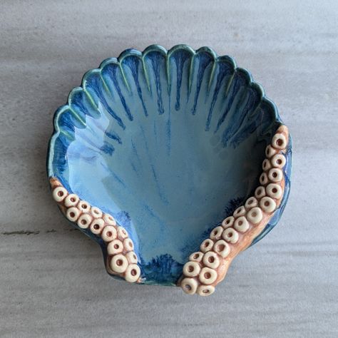 This handmade ceramic dish will add a unique touch to any room. The shell displays a variety of blues while the tentacles are a fleshy pink color. I also offer tentacle mugs, ring dishes, and trays so check out the other listings to own the complete set! Dimensions:  Large-8.25" x 6.75" x 1.25" Medium-4" x 4" x 1.25" *For new products and to get a behind-the-scenes view of a ceramic artist, check out my Instagram @27SistersStudio *All of my pottery is fired with ceramic glazes so the colors will Octopus Clay Art, Star Wars Ceramics, Clay Beach Ideas, Sea Ceramics Ideas, Under The Sea Ceramics, Creative Ceramics Ideas, Beach Ceramics, Ocean Ceramics, Shell Displays