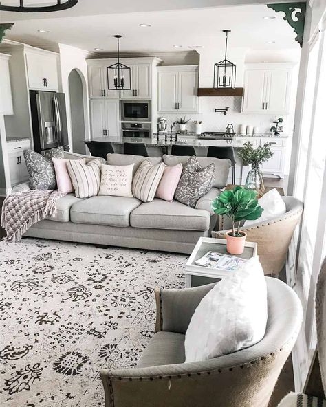 Light gray studded barrel chairs and matching couch furnish this kitchen living room combo. Black lantern pendants are displayed above a shiplap island with black stools. Double wall ovens and stainless steel appliances are surrounded by white cabinets. Small Kitchen Living Room Combo, Above Kitchen Cabinets Ideas, Shiplap Island, Small Kitchen Living Room, Kitchen Living Room Combo, Decorating Above Kitchen Cabinets Ideas, Rustic Wood Cabinets, Decorating Above Kitchen Cabinets, Kitchen Cabinets Ideas