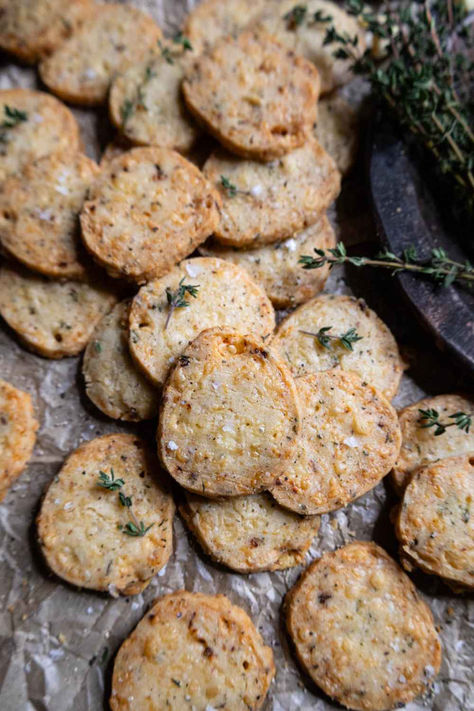 Savory shortbread cookies on crumbled parchment paper, topped with fresh thyme. Savoury Food Gifts, Thyme Shortbread Cookies, Savory Snack Bars, Savory Holiday Treats Gift Ideas, Cheddar Shortbread Cookies, Savoury Shortbread Cookies, Savory Christmas Cookies, Savoury Cookies Recipes, Savory Treats For Bake Sale